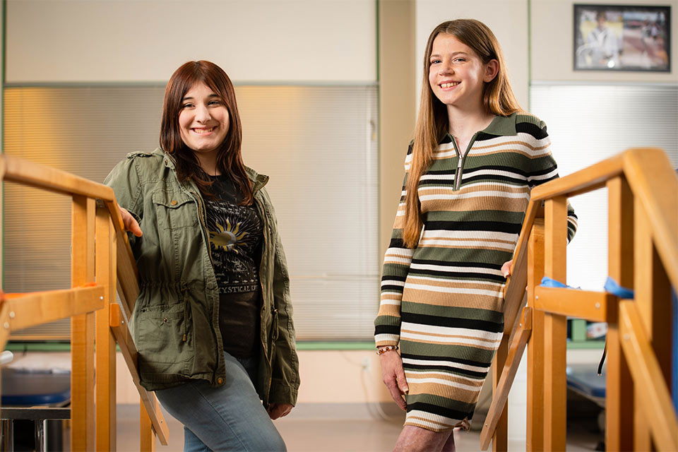 two patients standing in front of a wooden stair case.