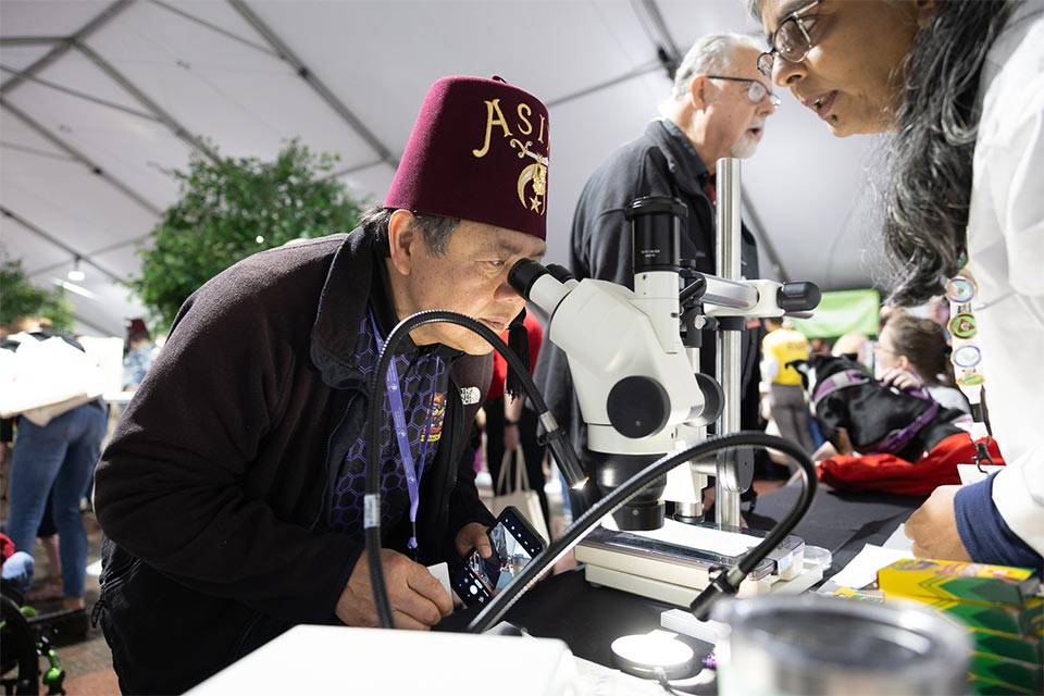 Shriner member looks through telescope at hospital tour event