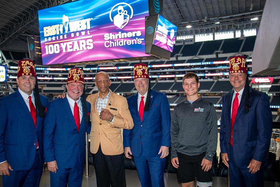 Four Shriners, one patient, one man at stadium, East West Shrine Bowl logo, 100 years, Shriners Children's logo