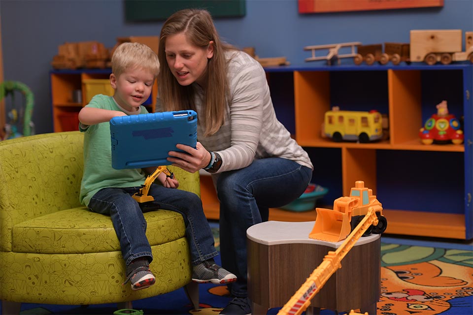 Male patient plays with tablet with female care giver.