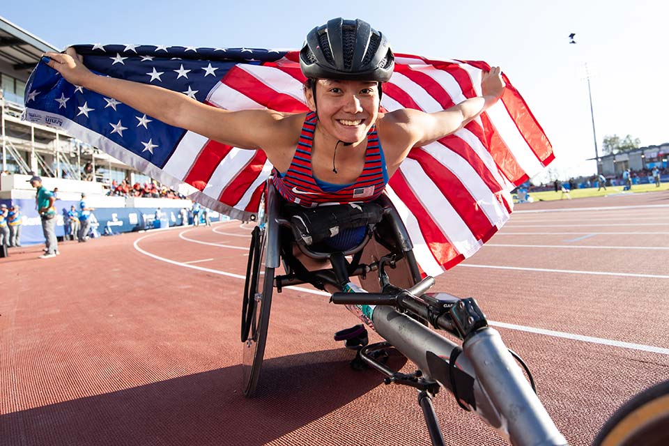 Hannah in racing wheelchair carrying american flag