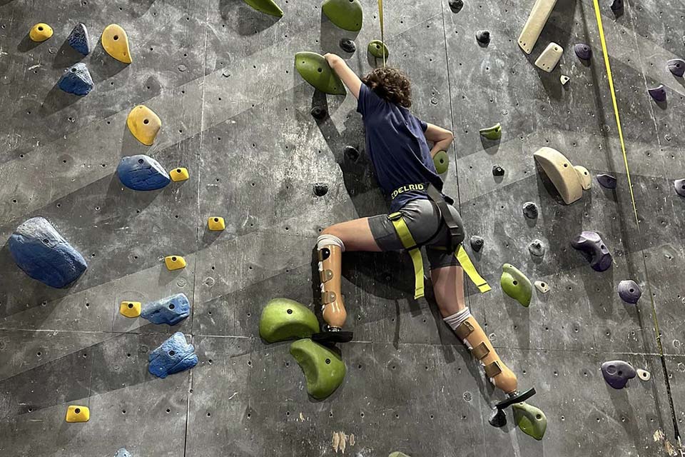 Grace climbing rock wall wearing prosthetic legs