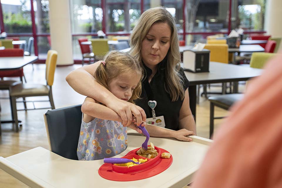 Une thérapeute aide une patiente à manger à la cafétéria