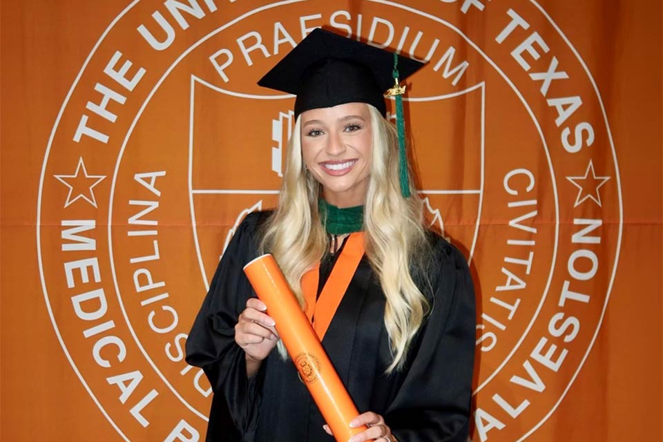 Jacy con toga y birrete de graduación, sosteniendo su diploma