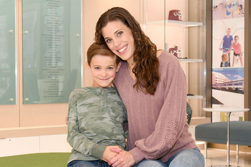 Un patient assis et souriant avec sa mère