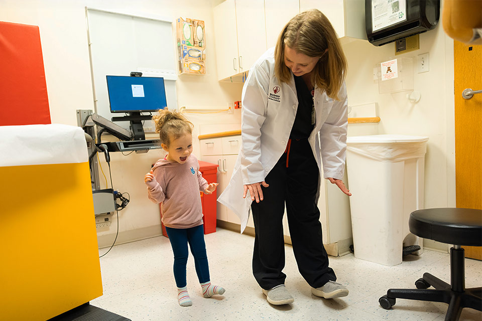 Patient walking and smiling with a care provider.