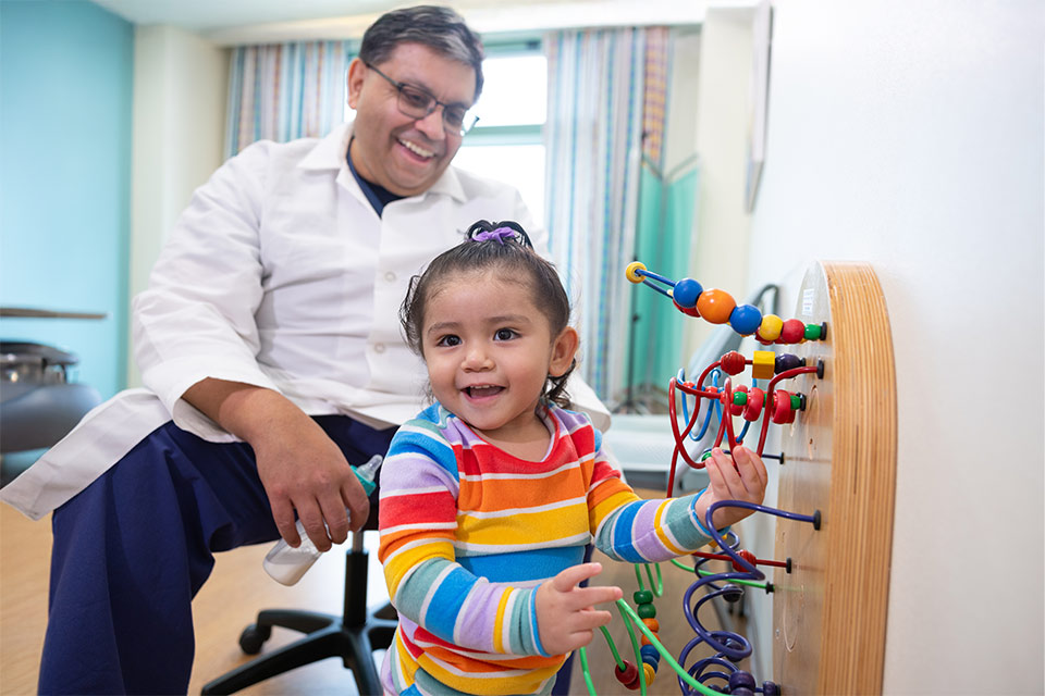 Patient playing while a care provider smiles in the background.